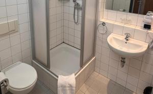 a bathroom with a shower and a toilet and a sink at DORMERO Express Hotel Passau in Passau
