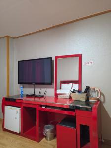 a red desk with a computer and a monitor on it at Happy Hotel in Jeju +15 photos
