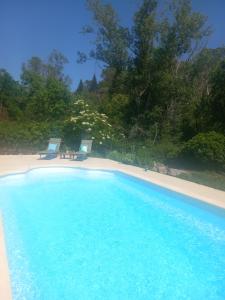 a swimming pool with two chairs on a beach at Charmante chambre d'hôtes "CARLA" avec piscine, Château de Favas in Bargemon