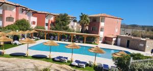 a swimming pool with umbrellas and chairs and buildings at Hôtel Maristella in Algajola