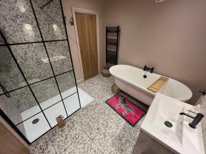 a bathroom with a bath tub and a sink at Copper Cottage in Devizes