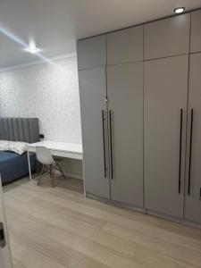 a room with white cabinets and a table and a bed at Квартира 2 комнаты in Balqash