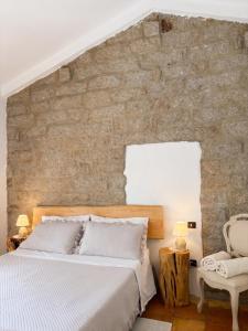 a bedroom with a large bed and a stone wall at Antico Stazzo Gallurese in Luogosanto