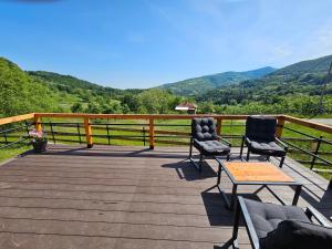 two chairs and a table on a wooden deck with mountains at Moonrise house Rudnik in Rudnik