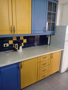 a kitchen with yellow and blue cabinets and a refrigerator at Nomad Villa Tirana in Tirana
