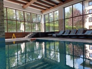 a swimming pool with chairs in a room with windows at Apartments Terra Harmony - 4 star free SPA resort, Golf i Skiing in Bansko