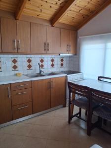 a kitchen with wooden cabinets and a table and a sink at Vila Klea in Ksamil