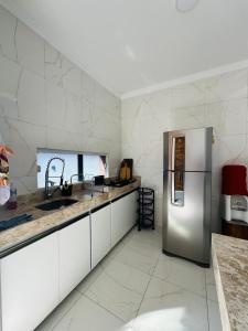 a kitchen with a stainless steel refrigerator and white cabinets at Casa Perfeita Paracuru in Paracuru
