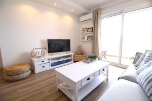 a living room with a white couch and a tv at Santa Ana 22 by homeprive in El Verger