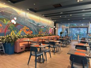 a restaurant with tables and chairs and a large mural at ibis Medellin in Medellín