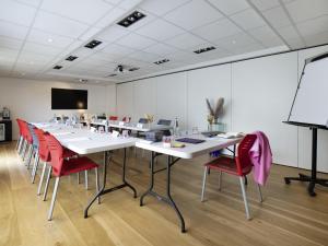 a conference room with white tables and red chairs at ibis Styles Rennes St. Gregoire in Saint-Grégoire
