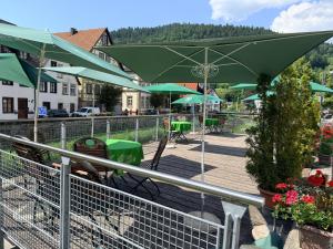 a deck with green umbrellas and tables and chairs at Zur alten Brücke in Schiltach