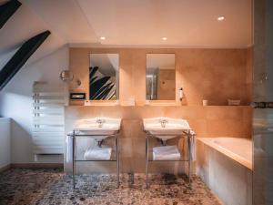 a bathroom with two sinks and a bath tub at Cour du Corbeau Hotel Strasbourg - MGallery Collection in Strasbourg +88 photos