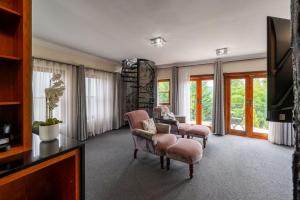 a living room with chairs and a tv and windows at IL Castello Boutique Hotel in Clarens