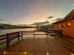two benches sitting on a boardwalk next to a river at Ville do Lago in Gravatá