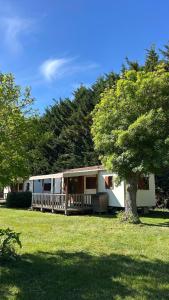 a small white caravan with a porch and a tree at Camping le Martin Pêcheur in Magné