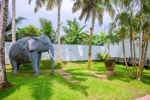 a statue of an elephant standing in the grass at LHK Dream Resort Matara in Palatuwa