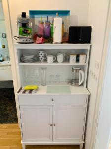 a white kitchen shelving unit with cups and utensils at Ahrweiler Seelchen in Bad Neuenahr-Ahrweiler