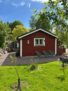 a red shed with two green chairs in the yard at Flamingon' in Undenäs