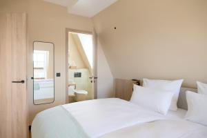 a bedroom with two white beds and a bathroom at Gezeiten Suites Büsumer Deichhausen - Neueröffnung in Büsumer Deichhausen