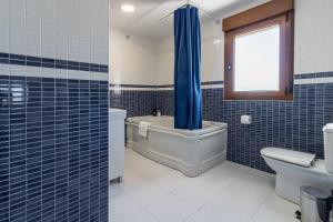a blue tiled bathroom with a tub and a toilet at El Rincón de Denver in Suances +32 photos