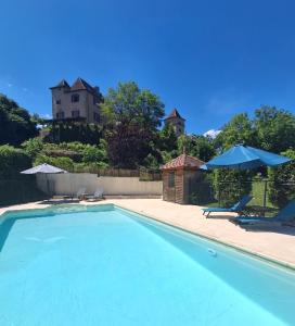 a swimming pool with two chairs and a house in the background at La Source de Diège in Loupiac