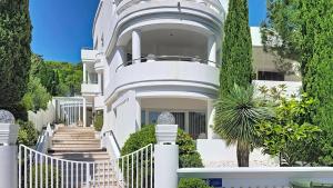 a white house with a white fence and trees at Villa Perla Baska in Baška