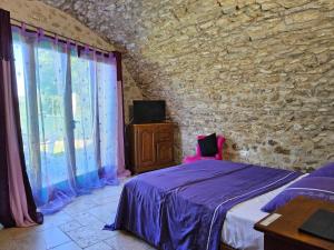 a bedroom with a bed and a stone wall at Gite 5 personnes SOLOGNE in Hargeville