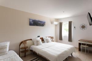 a bedroom with a bed and a desk and a window at Hôtel Maristella in Algajola
