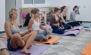 a group of women sitting in a yoga class at Happy Waves Morocco - Surf Hostel Tamraght in Tamraght Ou Fella