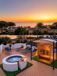 a hot tub on a patio with a sunset in the background at Villa Aida Luxury Apartments & Spa in Forio d'Ischia