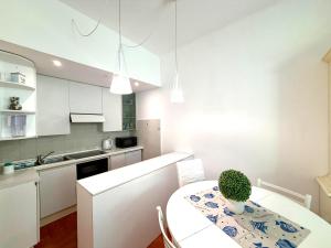 a white kitchen with a table with a plant on it at Excelsior Relaxing Apartment in Levanto