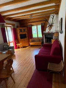 a living room with a red couch and a fireplace at Chalet Tornede in Stabiziane