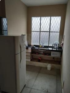 a kitchen with a refrigerator and two windows at Loft Campinho 2 in Estação Inhoaíba