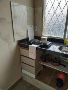 a small kitchen with a stove and a sink at Loft Campinho 2 in Estação Inhoaíba
