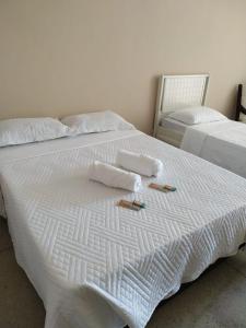two beds with towels and slippers on top of them at Loft Campinho 2 in Estação Inhoaíba