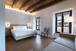 a bedroom with a white bed and two windows at Hotel Cittadellarte in Biella