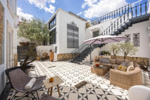 an outdoor patio with a couch and an umbrella at Casa de São Bento by PURUS in Coimbra