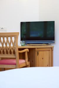 Ein Fernseher steht auf einem Holzständer mit einem Stuhl. in der Unterkunft Esterer in Grödig + 80 Fotos