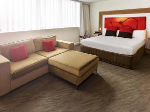 a hotel room with a couch and a bed at Novotel Sydney West HQ in Rooty Hill