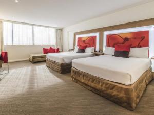 a hotel room with two beds and a couch at Novotel Sydney West HQ in Rooty Hill