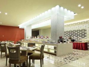 a restaurant with a table and chairs and a buffet at Mercure Padang in Padang