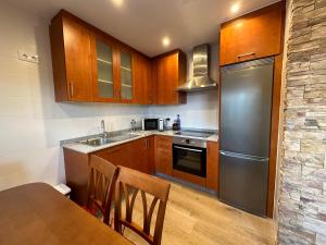 a kitchen with wooden cabinets and a stainless steel refrigerator at Apartamento do Lagar, Praia da Abrela in O Vicedo +17 photos