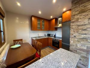 a kitchen with a wooden table and a counter top at Apartamento do Lagar, Praia da Abrela in O Vicedo