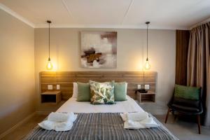 a bedroom with a bed with two towels on it at Arebbusch Travel Lodge in Windhoek