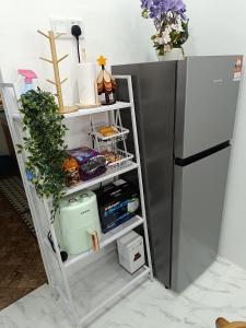 a white shelving unit next to a refrigerator at D'Berang Rumah Singgah in Kuala Berang