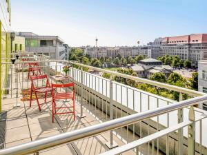 a balcony with red chairs and a view of a city at ibis Berlin Kurfuerstendamm in Berlin