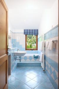 ein blau gefliestes Badezimmer mit Waschbecken und Badewanne in der Unterkunft Esterer in Grödig