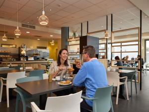a man and woman sitting at a table in a restaurant at ibis Styles Zeebrugge in Zeebrugge