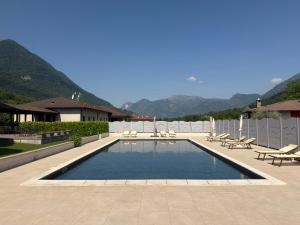 a swimming pool with chairs and tables and mountains at Hotel Merloni in Grandola ed Uniti